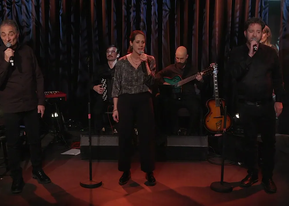 Trois chanteurs de L’Écho du Mont Brun au micro pendant une répétition, devant les musiciens